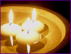 Three lit floating candles in a shallow stone bowl